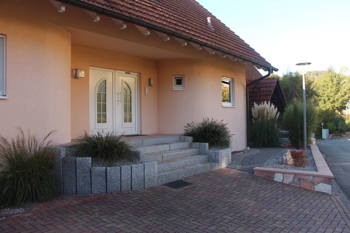 Eingang eines modernen Hauses mit einer Stufenanlage und üppiger Bepflanzung.